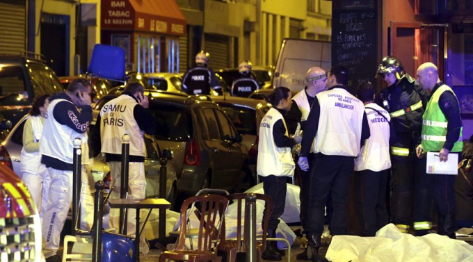 A general view of the scene shows rescue service personnel working near the covered bodies outside a restaurant following a shooting incident in Paris